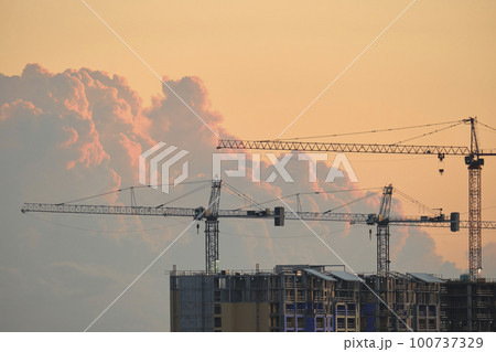 Tower cranes and frame structure of high residential apartment buildings at construction site. Real estate development 100737329