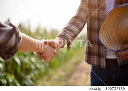 Close up view of farmers checking hands and making a deal with female, reaching agreement deal 100737389