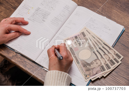 【家計簿をつける主婦と一万円札】 【家計簿をつける主婦と一万円札】 100737703