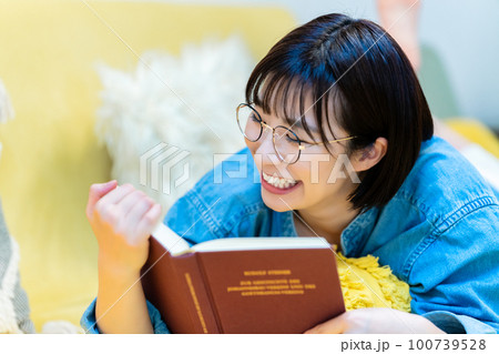 ソファーに寝転んで本を読む女性 ソファーに寝転んで本を読む女性 100739528