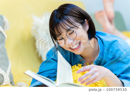 ソファーに寝転んで本を読む女性 ソファーに寝転んで本を読む女性 100739530