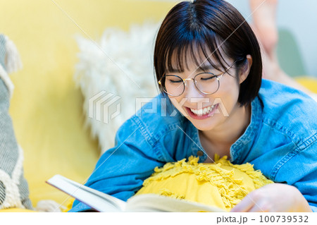 ソファーに寝転んで本を読む女性 ソファーに寝転んで本を読む女性 100739532