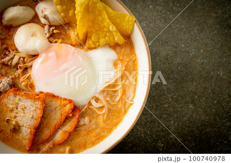 Rice vermicelli noodles with meatball, roasted pork and egg in spicy soup 100740978