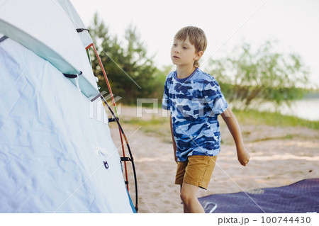 cute little caucasian boy helping to put up a tent. Family camping concept 100744430