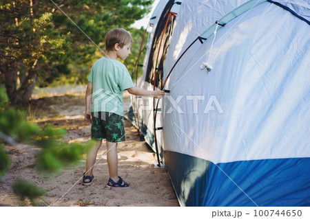 cute little caucasian boy helping to put up a tent. Family camping concept cute little caucasian boy helping to put up a tent. Family camping concept 100744650