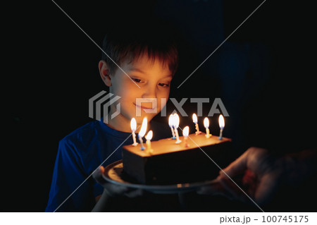 little cute caucasian boy making a wish before puffing out a candle on cake on his 9 birthday 100745175