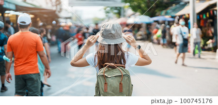 woman traveler visiting in Bangkok, Tourist with backpack and hat sightseeing in Chatuchak Weekend Market, landmark and popular attractions in Bangkok, Thailand. Travel in Southeast Asia concept 100745176