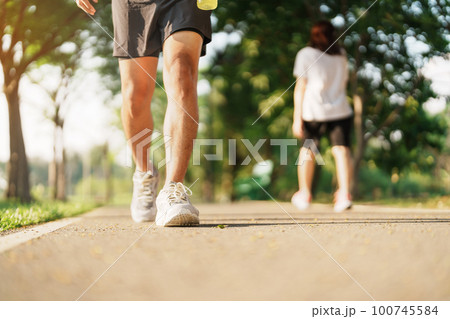 man jogging and walking on the road at morning with Energy Drink water, adult male in sport shoes running in the park outside. Exercise, wellness, healthy lifestyle and wellbeing concepts 100745584