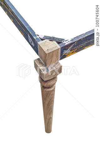 Wooden carved leg of solid oak with metal table frame during manufacturing process of dining table isolated on white background Wooden carved leg of solid oak with metal table frame during manufacturing process of dining table isolated on white background 100745604