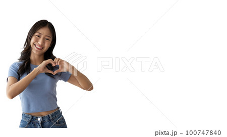 Asian young woman with bright smile making heart symbol shape with hands, Symbol of love and romance, Give each other cuteness and create smiles for each other, Positive thinking concept. 100747840