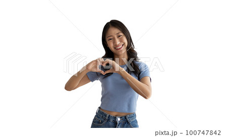 Asian young woman with bright smile making heart symbol shape with hands, Symbol of love and romance, Give each other cuteness and create smiles for each other, Positive thinking concept. 100747842