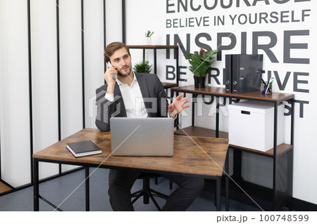 a professional broker calls a client about a deal while in the office a professional broker calls a client about a deal while in the office 100748599