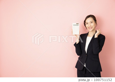 ピンクバックでネイビーのスーツを着て白い電卓を持つ女性 100751152