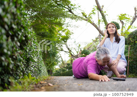 Asian senior woman fell down on lying floor because faint and limb weakness and pain from accident and woman came to help support and call emergency. Concept of old elderly insurance and health care Asian senior woman fell down on lying floor because faint and limb weakness and pain from accident and woman came to help support and call emergency. Concept of old elderly insurance and health care 100752949