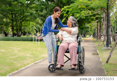 Asian careful caregiver or nurse taking care of the patient in a wheelchair. Concept of happy retirement with care from a caregiver and Savings and senior health insurance, a Happy family Asian careful caregiver or nurse taking care of the patient in a wheelchair. Concept of happy retirement with care from a caregiver and Savings and senior health insurance, a Happy family 100753153