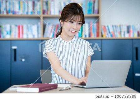 図書館でノートパソコンを使う若い女性 100753589