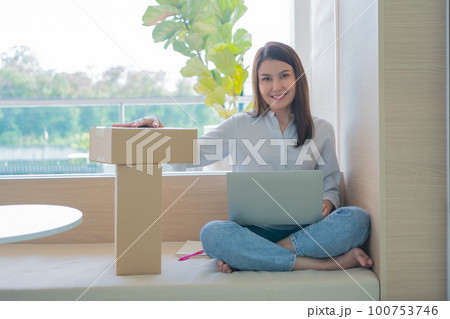 Happy young Asian woman entrepreneur, Hold package and Smile for sale success of online shopping store at home office, Concept of merchant, small business, online business and eCommerce. Happy young Asian woman entrepreneur, Hold package and Smile for sale success of online shopping store at home office, Concept of merchant, small business, online business and eCommerce. 100753746