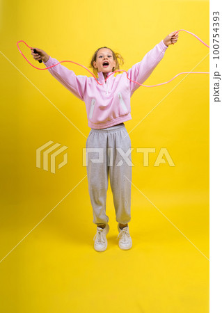 Adorable female child with skipping rope jumping in studio 100754393