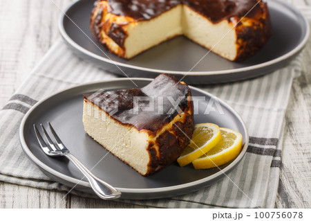 Basque cheesecake with a creamy center and a deeply caramelized crust top and bottom closeup on the plate. Horizontal 100756078