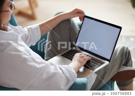Mockup white screen laptop woman using computer sitting on armchair at home, back view, focus on screen Mockup white screen laptop woman using computer sitting on armchair at home, back view, focus on screen 100756983