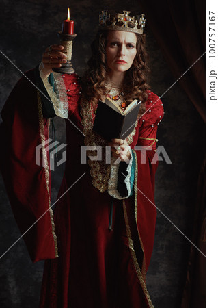 Full length portrait of medieval queen in red dress with book 100757167