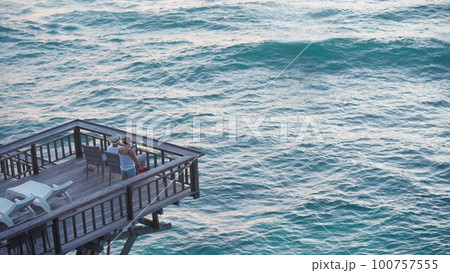 Silhouette of a young couple filming a sunset on a terrace by the sea or ocean on a mobile phone Silhouette of a young couple filming a sunset on a terrace by the sea or ocean on a mobile phone 100757555