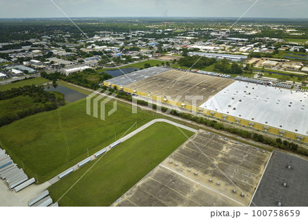 High angle view of big commercial shipping center with many freight trucks unloading and uploading goods for further distribution. Global economy concept 100758659