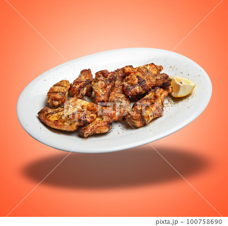 Floating White plate with roasted chicken wings 100758690