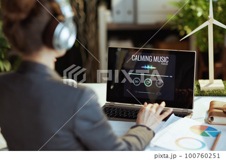 Seen from behind business woman listening to music Seen from behind business woman listening to music 100760251
