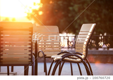 Closeup of outdoors cafe chairs and table at sunset on city street Closeup of outdoors cafe chairs and table at sunset on city street 100760720