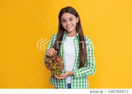 happy teen girl with fresh grapes bunch on yellow background happy teen girl with fresh grapes bunch on yellow background 100760972