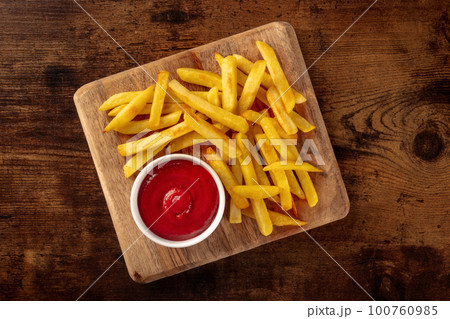 French fries, potato snack with ketchup, fast food on a wooden table 100760985