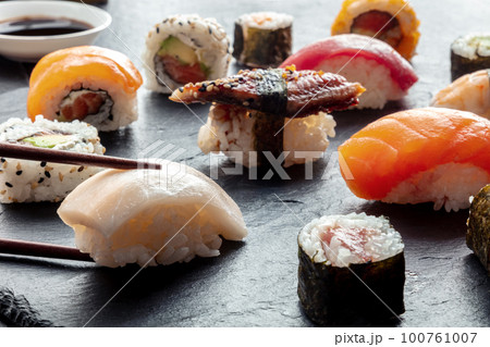 Sushi with chopsticks. Rolls, maki, nigiri on a black background, Japanese food 100761007