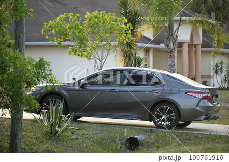 Car parked in front of wide garage double door on concrete driveway of new modern american house Car parked in front of wide garage double door on concrete driveway of new modern american house 100761916