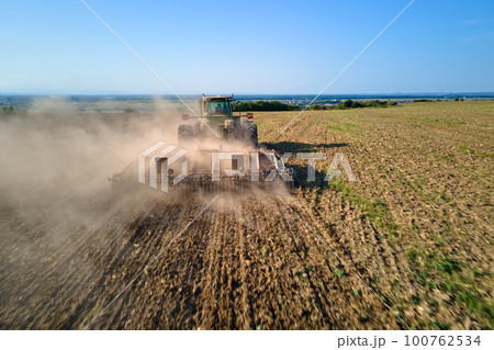 Aerial view of tractor plowing agriculural farm field preparing soil for seeding in summer Aerial view of tractor plowing agriculural farm field preparing soil for seeding in summer 100762534