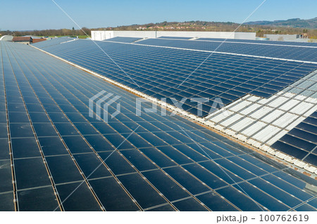 Aerial view of solar power plant with blue photovoltaic panels mounted on industrial building roof for producing green ecological electricity. Production of sustainable energy concept 100762619