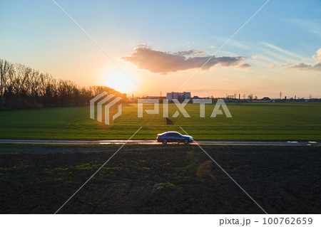 Aerial view of sedan car driving fast on dirt road at sunset. Traveling by vehicle concept. Aerial view of sedan car driving fast on dirt road at sunset. Traveling by vehicle concept. 100762659