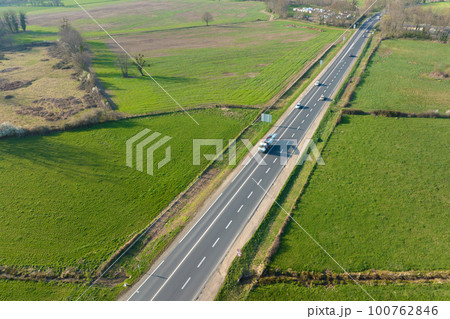 Aerial view of intercity road between green agricultural fields with fast driving cars. Top view from drone of highway traffic 100762846