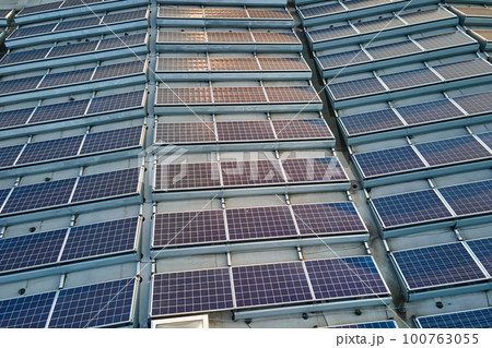 Aerial view of blue photovoltaic solar panels mounted on industrial building roof for producing green ecological electricity. Production of sustainable energy concept 100763055