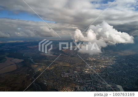 Aerial view from airplane window at high altitude of distant city covered with puffy cumulus clouds forming before rainstorm Aerial view from airplane window at high altitude of distant city covered with puffy cumulus clouds forming before rainstorm 100763169