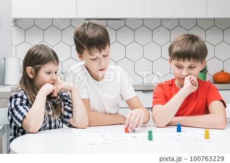 Concentrated worried thoughtful children play board game, make move with pieces. Family active games. Kid brain skill Concentrated worried thoughtful children play board game, make move with pieces. Family active games. Kid brain skill 100763229