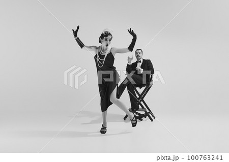 Emotional couple in love wearing old-time evening fancy outfits entertaining together. Monochrome. Eras comparison concept 100763241