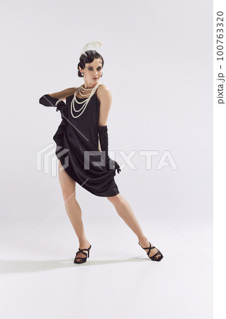 Photo of charming woman wearing chic vintage clothes dancing and looking at camera over white background 100763320
