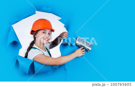 happy kid engineer with plastering spatula tool in hard hat, copy space, activity 100765605