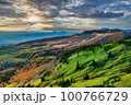 朝焼けをする紅葉と緑の山の斜面 100766729