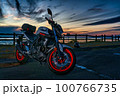 夕焼けと光を反射する赤いバイクと湖 100766735
