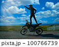 オフロードのバイクの上に立って太陽を指差す人 100766739