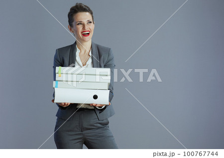 happy stylish business woman looking at copy space against grey 100767744