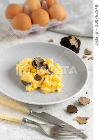Scrambled eggs with fresh black truffles from Italy served in a plate close up, gourmet breakfast 100768548