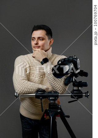 photographer in sweater near digital camera on tripod photographer in sweater near digital camera on tripod 100769704